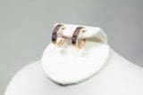 A pair of Amethyst Earrings displayed on a white stand against a gray background.