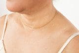 Close-up of a person's neck and shoulder wearing a spaghetti strap top and a Solid 18k Yellow Saudi Gold Chains 0.75g necklace.