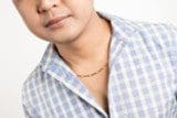 A person wearing a light blue and white checkered shirt and an 18k Solid Yellow Gold Saudi Chain 4.80g. Only the lower part of the face and upper torso are visible.