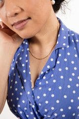 A person wearing a blue polka dot dress and a 18k Solid Yellow Gold Saudi Chain 7.8g, with the bottom half of their face visible.
