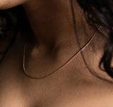 Close-up of a person's neck and collarbone with a Plain Rose Gold Chain resting on the skin. Dark hair is partially visible to the right.