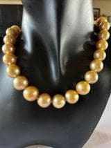 A necklace of Golden South Sea Pearls is displayed on a black mannequin bust.