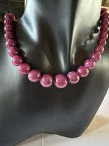 A Natural Red Sapphire 418ct displayed on a black mannequin bust.